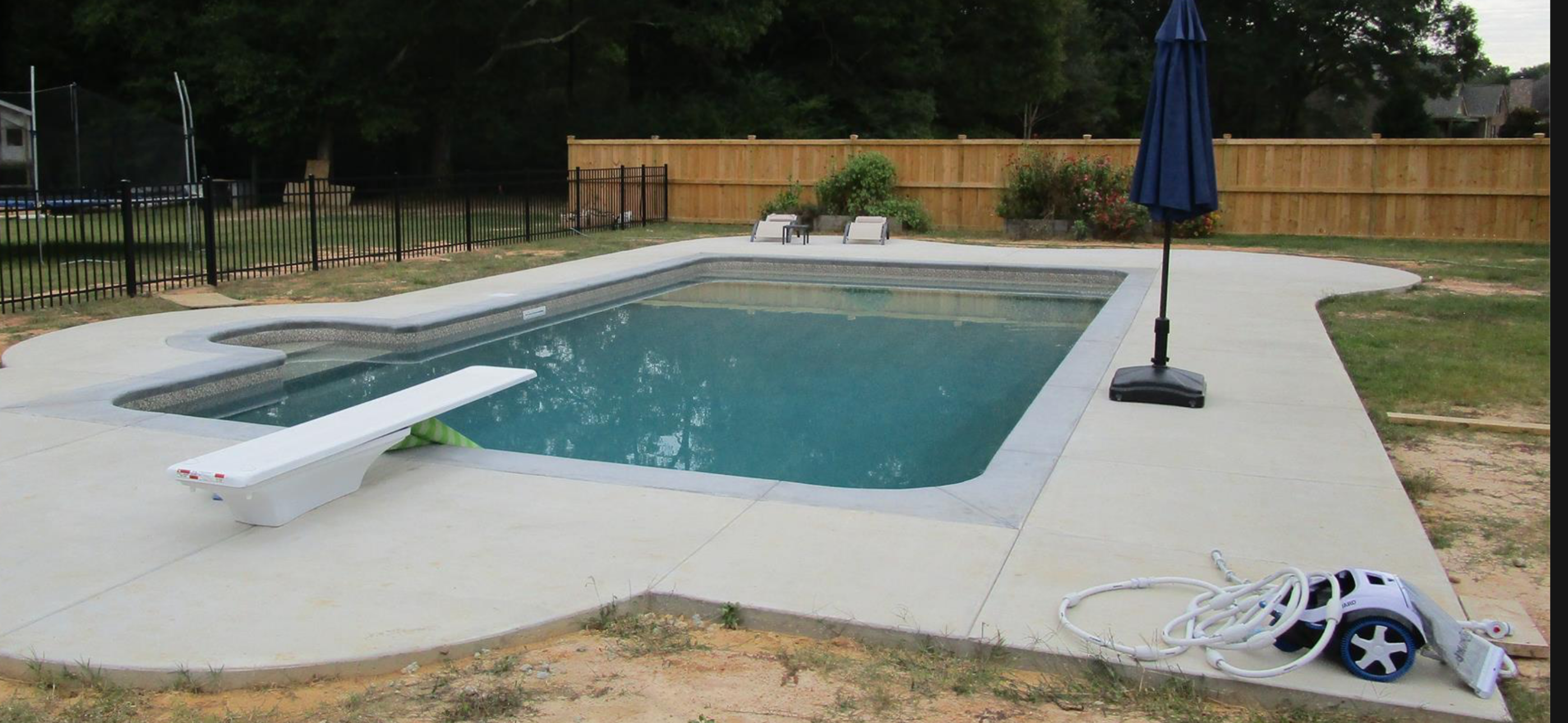 Rectangular vinyl liner pool with diving board and wood privacy fence