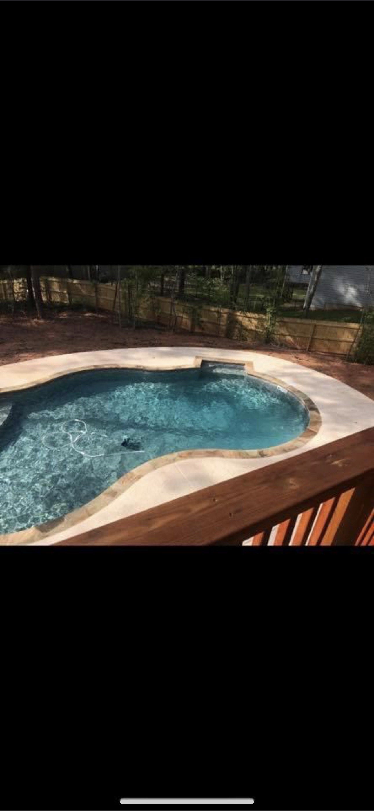 Freeform vinyl liner pool viewed from deck with wooden railing
