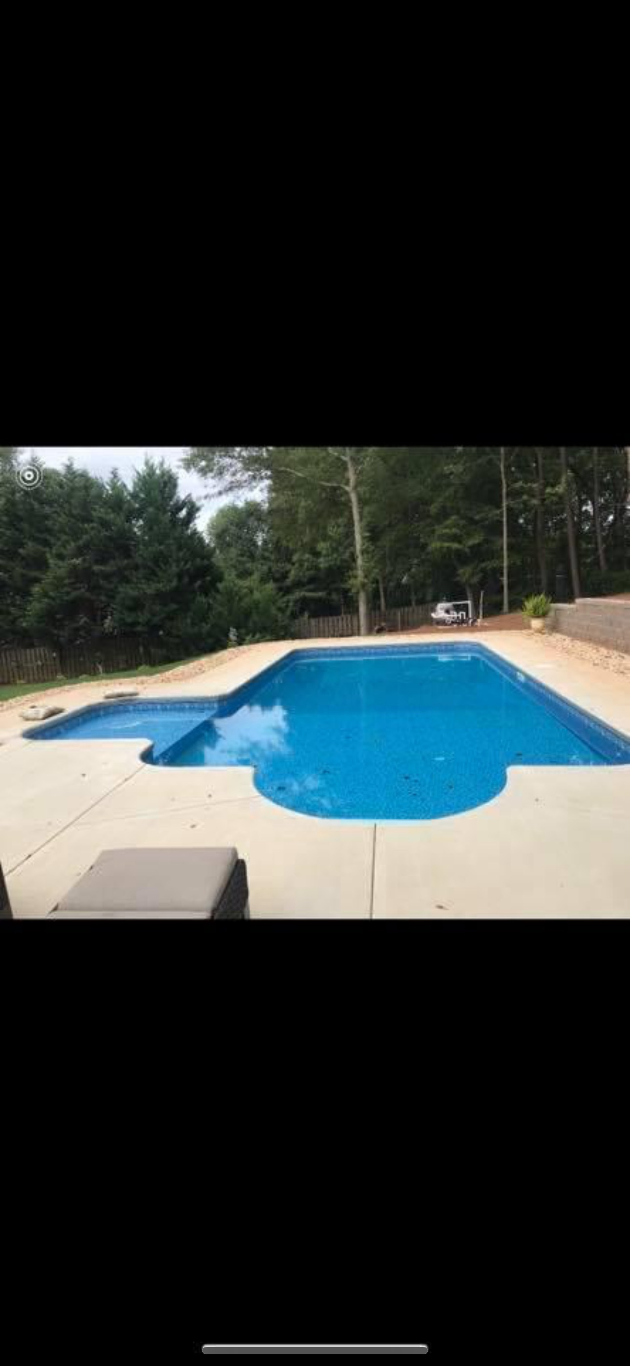 L-shaped vinyl liner pool with bright blue water and lush backyard